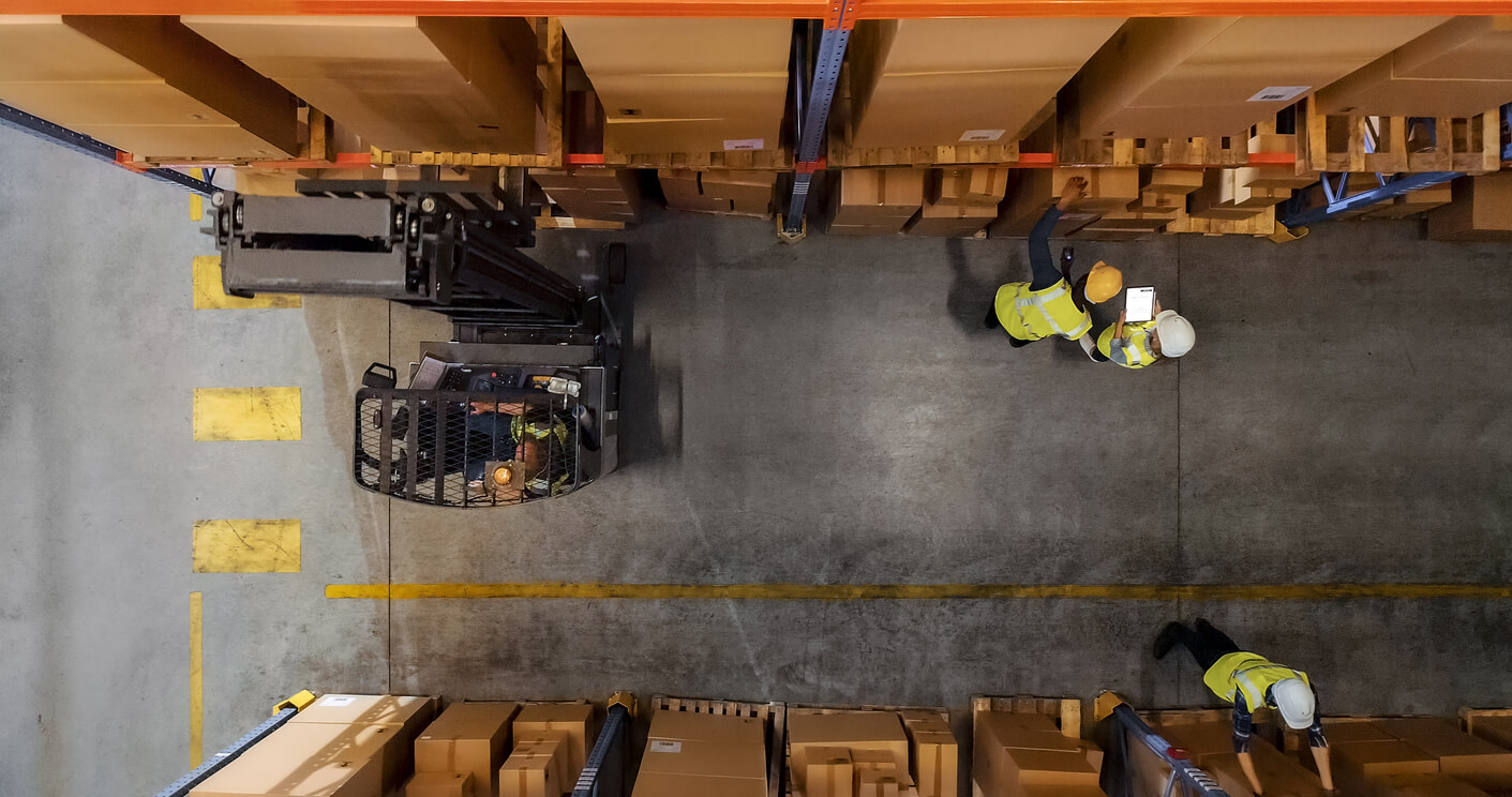 Top-Down Shot: Electric Forklift Truck Operator Lifts Pallet with Cardboard Box of in a Big Retail Warehouse a Shelf