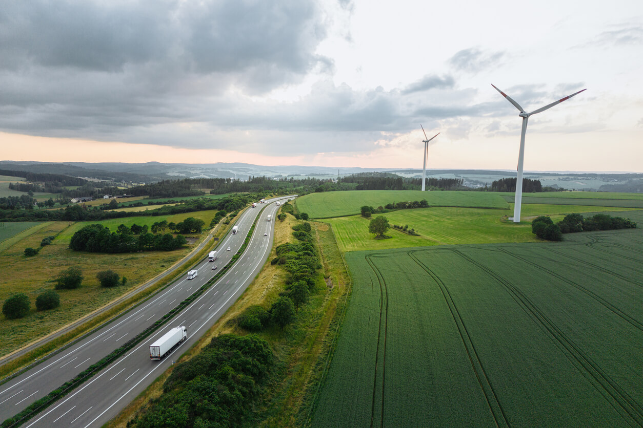 Wind farm next to a highway in the sunset with backlight seen from an aerial view